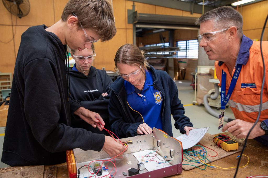 Abbot Point Operations Fourth Year Engineering (Fitting and Turning) Apprentice Bryce Doyle instructs Bowen State High School students at the QMEA's Tradie for a Day workshop; Image Source: Supplied