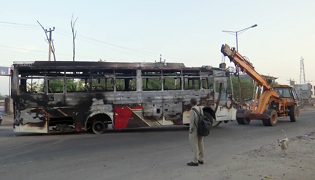 A damaged bus being removed after a clash broke out, in Haryana's Nuh on Tuesday. A violent clash erupted between two groups during the Hindu procession. (ANI Photo)
