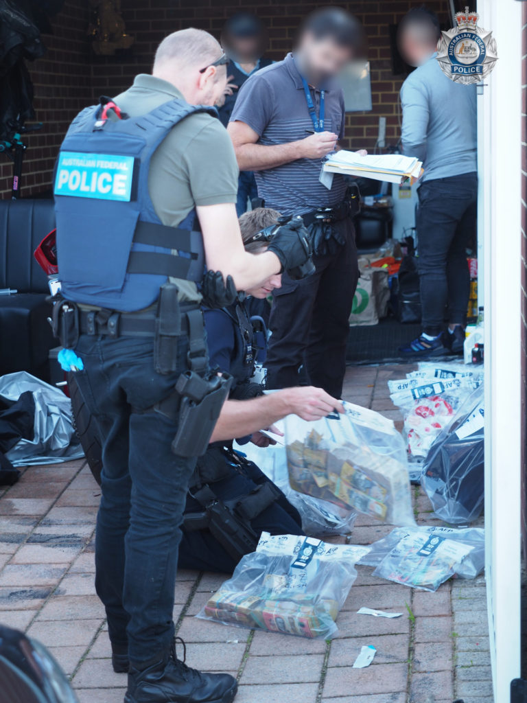 May 2022 AFP going through seized items arrested man in grey logo 4