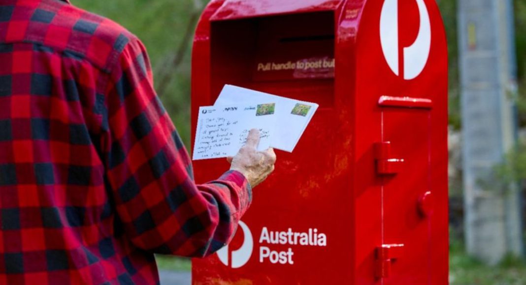 Image: Photo of a man posting into a street posting box (Source: Australia Post)