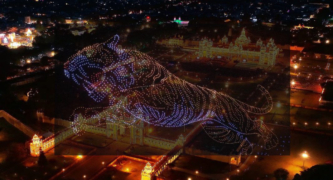 Image: Tiger created using drones over the Torchlight Parade Ground at Bannimantap in Mysuru (Source: Screenshot - The Hindu) and 100,000 incandescent bulbs are used to illuminate the Mysore Palace (Source: X - @sriharikaranth)