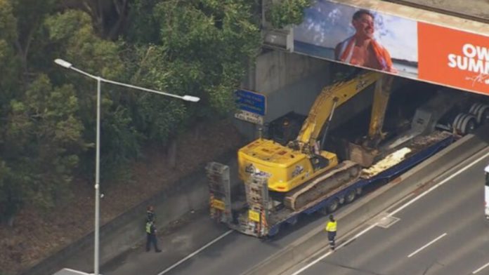 Image: The excavator became trapped at the on-ramp to Citylink at Batman Avenue (Source: Nine News screenshot)